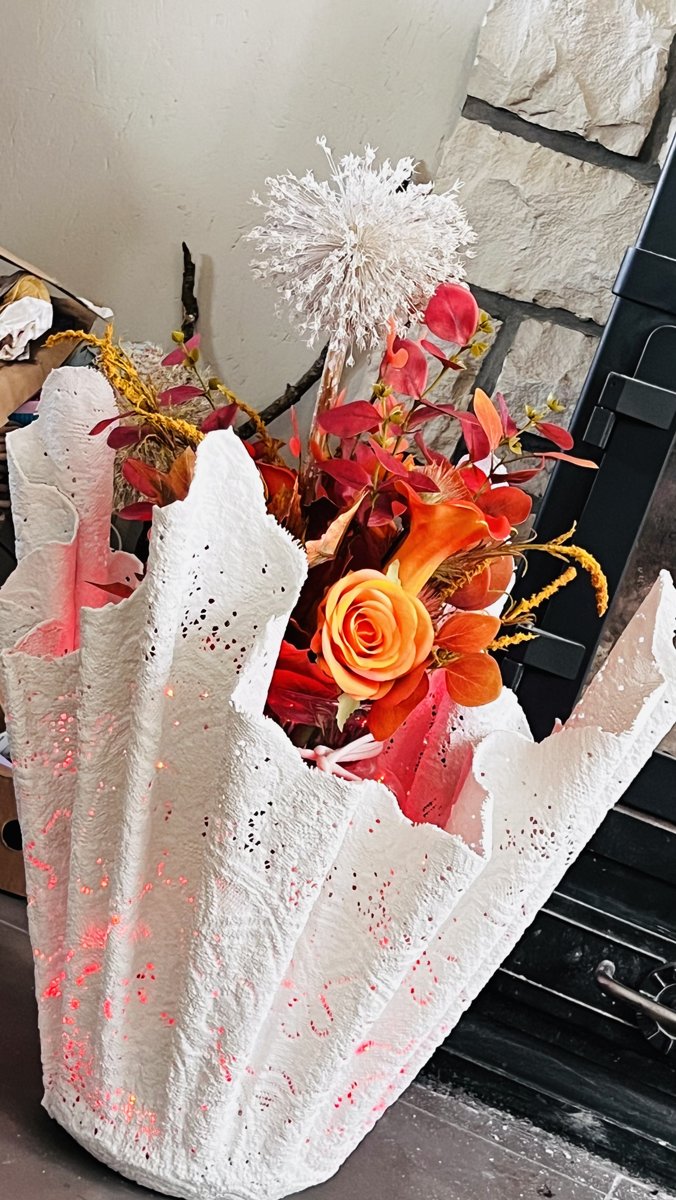Dentelle de Bruges Lamp habillée de fleurs oranges et rouges, exemple de collaboration florale autour d'un objet multipotentiel